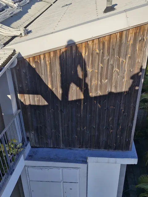 Bardage bois gris d'une façade vu depuis le toit, avant ponçage