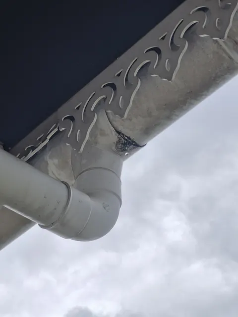 Descente de gouttière en PVC sous un débord de toit, vue du dessous